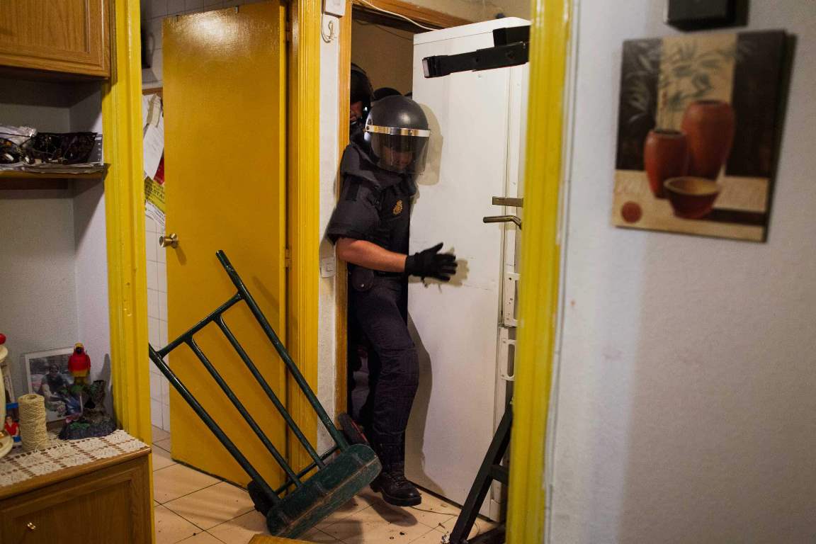 Police remove the door and push refrigerator as they break into Maria Isabel Rodriguez Romero's apartment to evict her and her family in Madrid, Spain, Wednesday, Sept. 25, 2013. Rodriguez Romero, 45 years old, has 6 family members, all unemployed including a 8 year-old daughter, and her mother with a bipolar syndrome. They live together in an apartment of the State City Hall Housing Company (EMVS) for 24 years and they have paid a debt of 1200 euros but EMVS informed them they have to move out. EMVS, a state company with an aim to give housing solutions for people in need, sold 1.860 state apartments to private investors in 2013. The eviction was executed despite of the resistance of dozens of Victims' Mortgage Platform (PAH) activists. (AP Photo/Andres Kudacki)