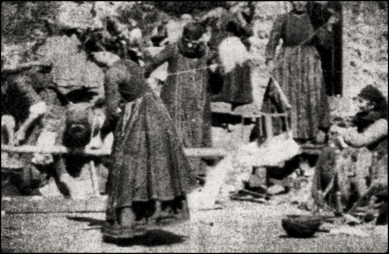 Γυναίκες γνέθουν, στην αυλή σπιτιού στο χωριό Αβδέλλα της Πίνδου. Στο κέντρο, σκυμμένη η γιαγιά των Μανάκια. Πλάνο από τις «Υφάντρες», πρώτη ταινιά στα Βαλκάνια (1905).